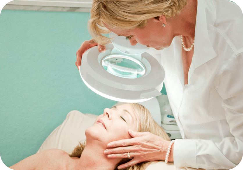 A woman is getting her face cleaned by an esthetician.