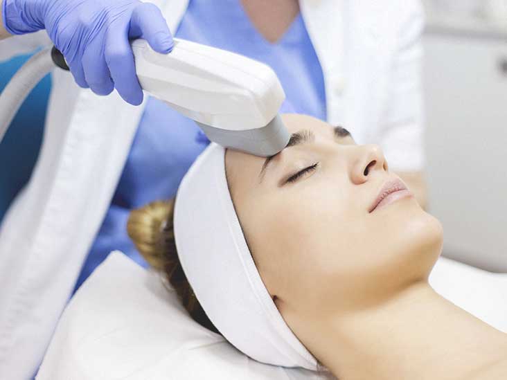 A woman getting her face cleaned with an electric device.