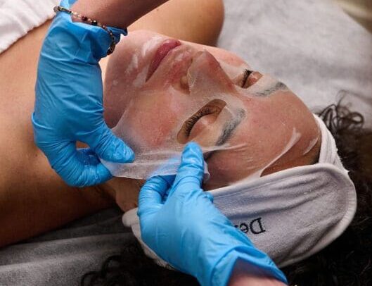 A woman is getting her face waxed by an esthetician.