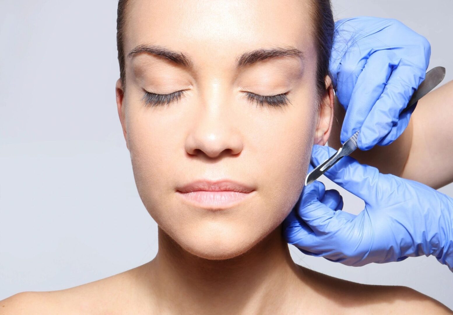 A woman getting her face waxed by a person.